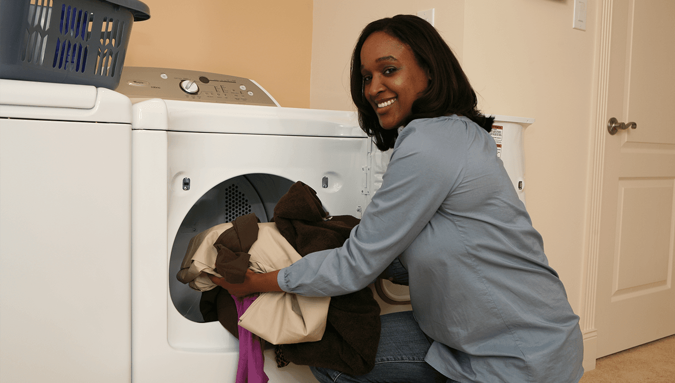 Woman putting towels into a natural gas dryer