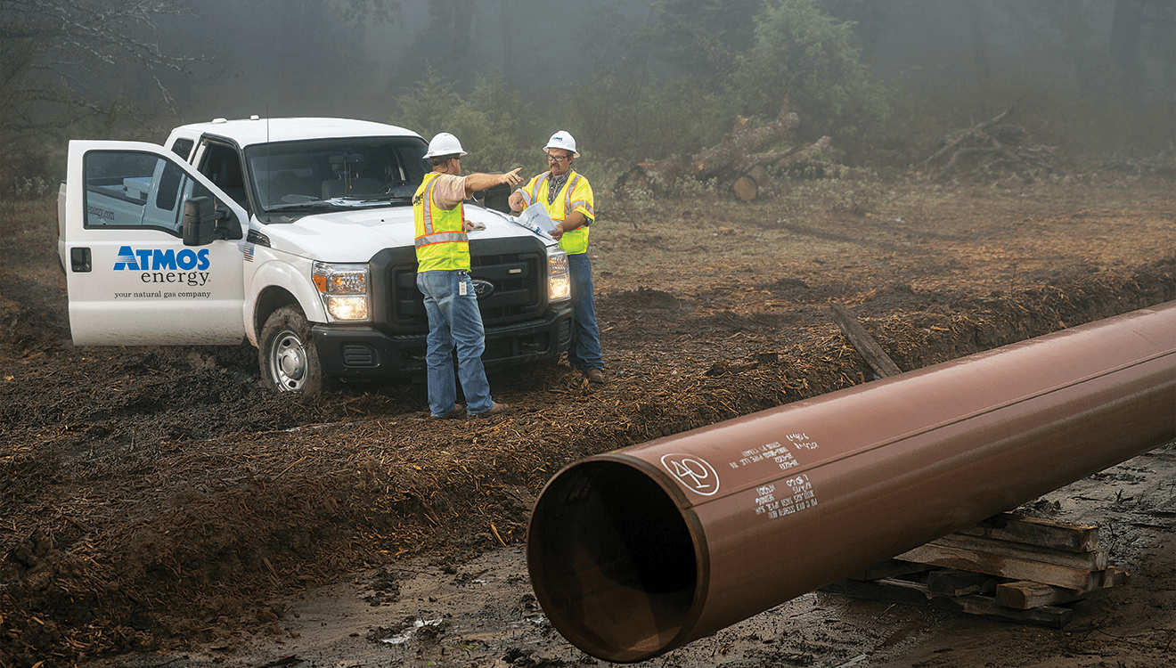 Atmos Energy truck parked in a muddy field with two service inspecting large natural gas pipeline